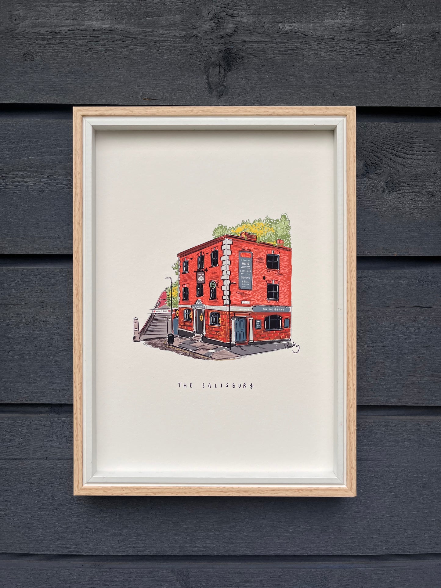 Salisbury venue in Manchester art print, framed in a light wooden frame hung on a wooden dark grey panelled wall 