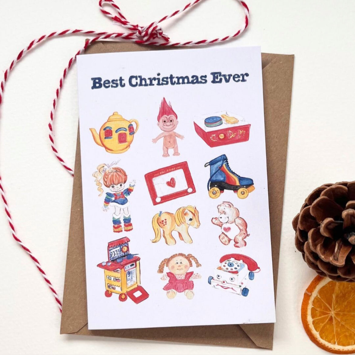 White Best Christmas Ever card and accompanying brown envelope features 11 retro toys illustrated in colour